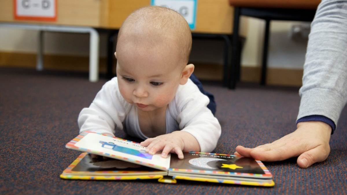 A baby looking at a book in a library