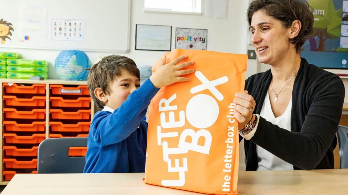 A child and a teacher opening a Letterbox Club parcel together