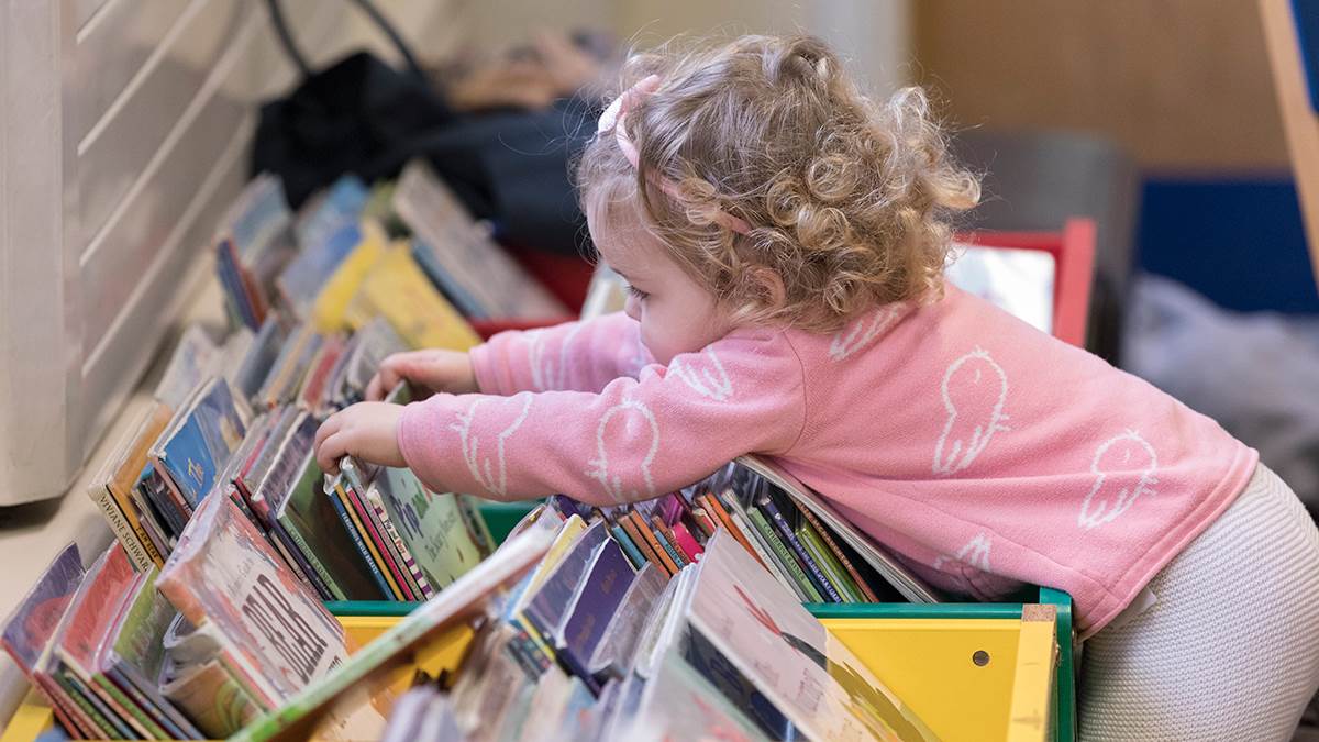 A photo of a girl looking through library books