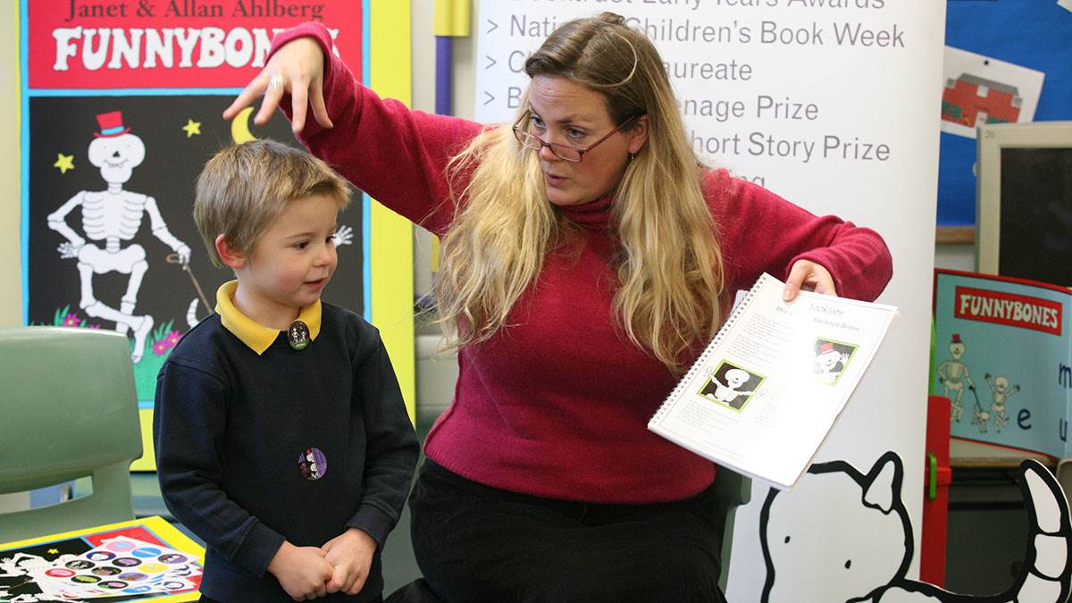 A young student and teacher enjoy reading Funnybones