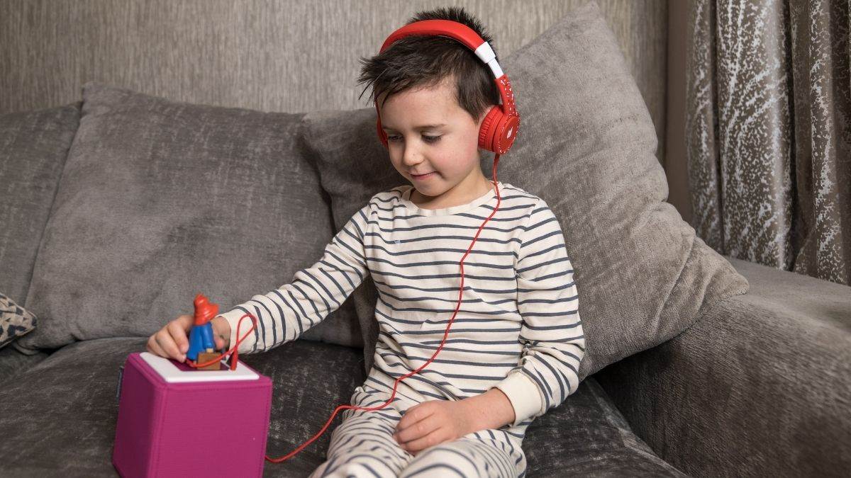 Little boy wearing headphones and using a Toniebox