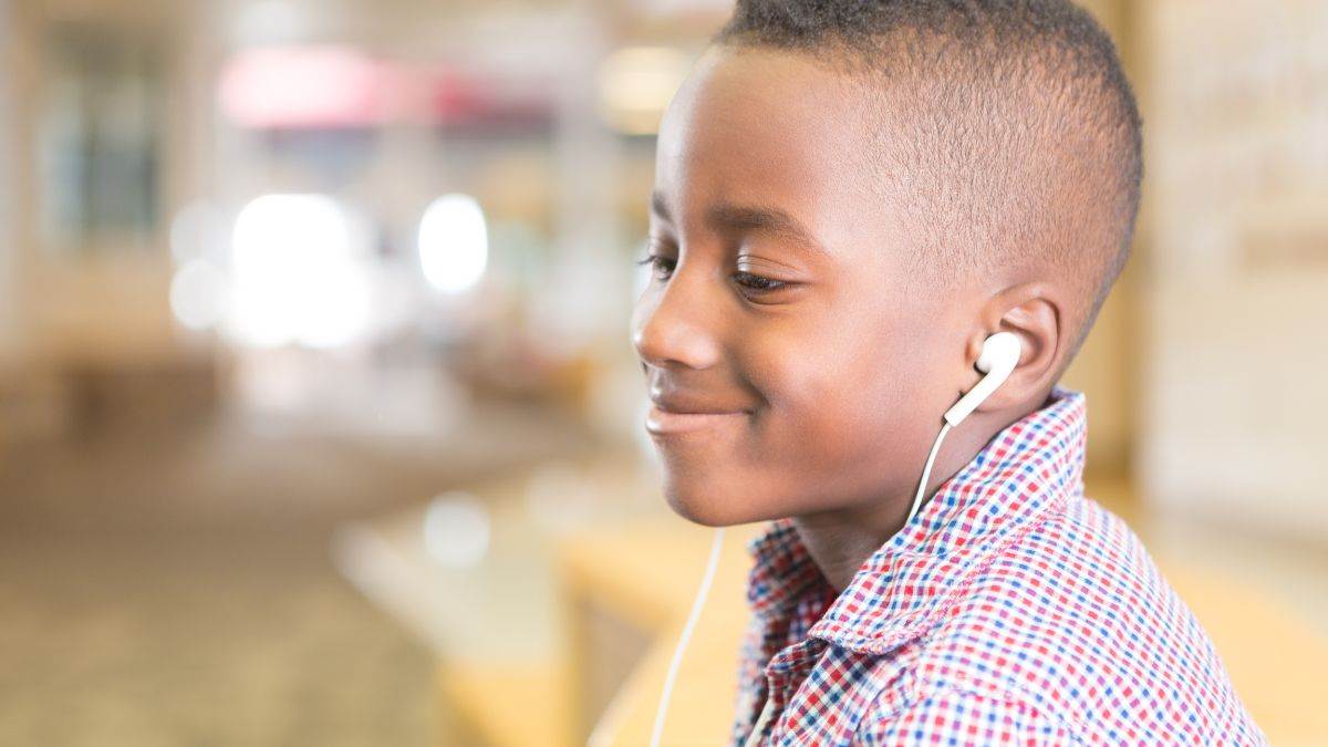 A child smiling while listening to earphones