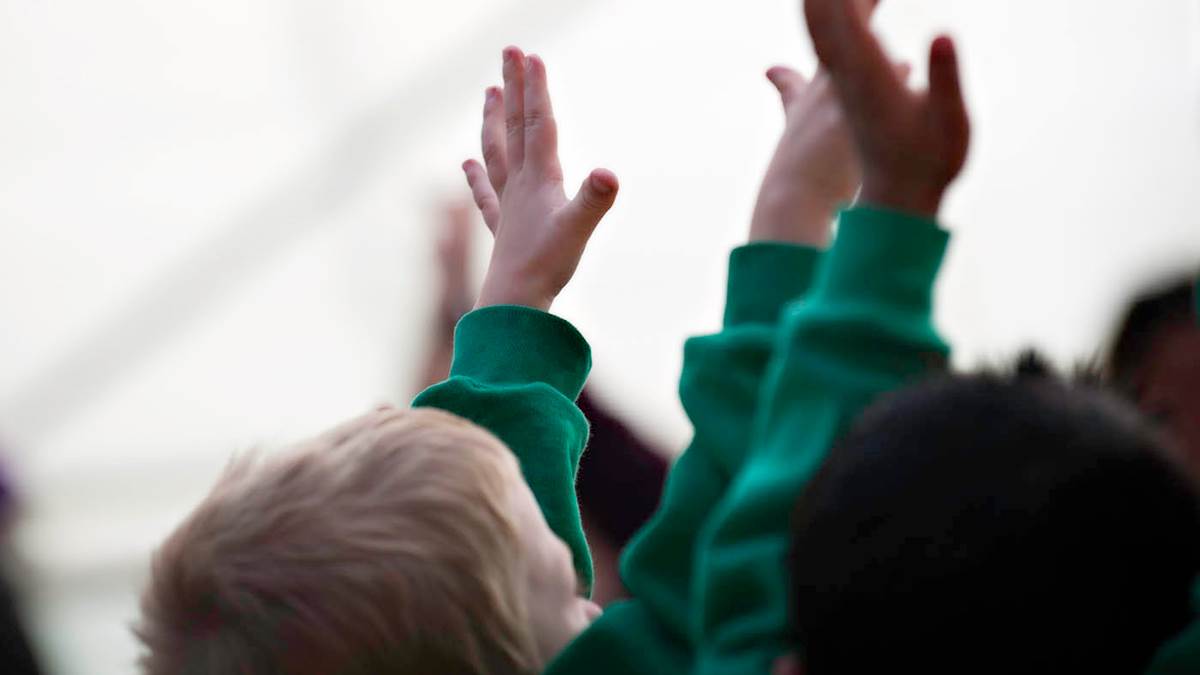 A photo of children in school uniform with their hands in the air