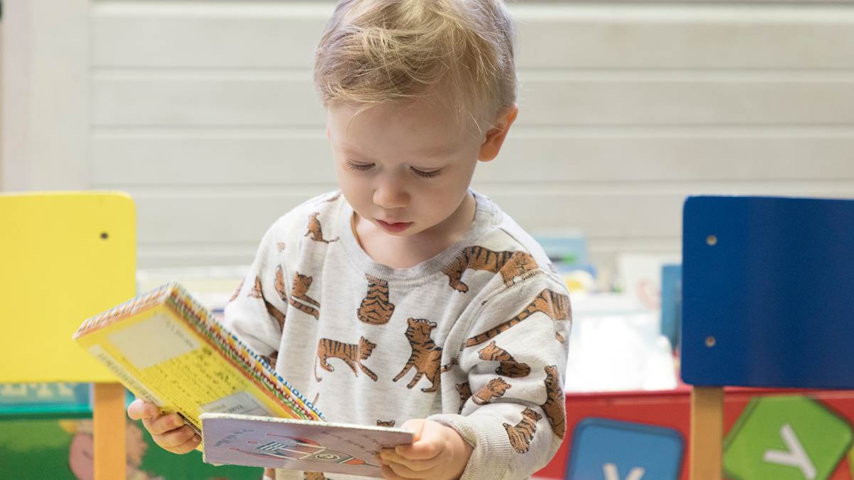 A photo of a young boy looking at books in the library, holding a book in each hand