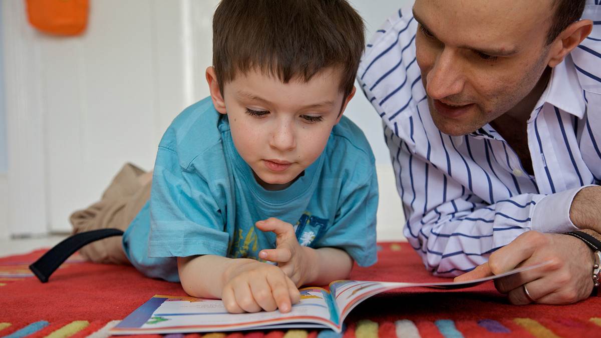Boy and dad reading together lying down