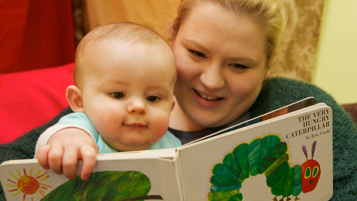 Mum and baby reading The Very Hungry Caterpillar by Eric Carle 