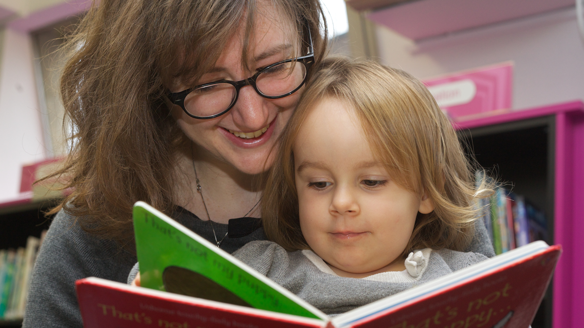 A little girl and her mum reading in a library